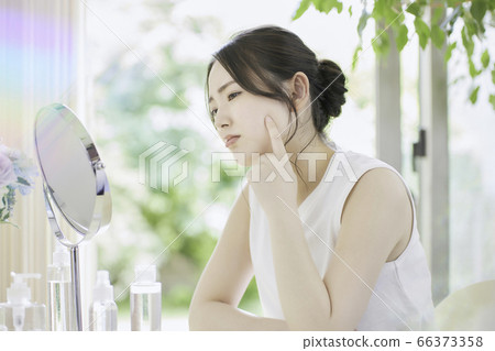 一名年輕女子在客廳裡照顧她的皮膚[擔心] 66373358