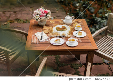 Afternoon tea basque burnt cheesecake and tea cup with teapot on wooden table. Afternoon tea basque burnt cheesecake and tea cup with teapot on wooden table. 66375378