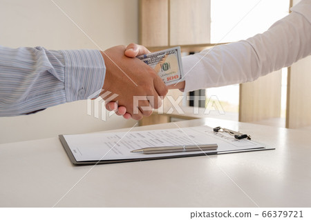 photo of Businessmen shake hands and dollar note, sign a contract to bribe corruption in the company photo of Businessmen shake hands and dollar note, sign a contract to bribe corruption in the company 66379721
