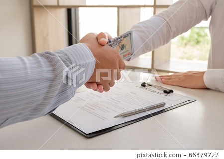 photo of Businessmen shake hands and dollar note, sign a contract to bribe corruption in the company photo of Businessmen shake hands and dollar note, sign a contract to bribe corruption in the company 66379722