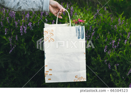 Hand holding shopping paper bags on a natural Hand holding shopping paper bags on a natural 66384523