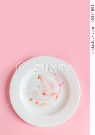 Dirty plate with food leftovers on pink 66384691