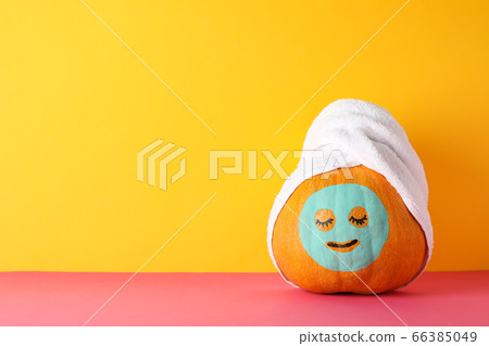 Pumpkin with facial mask and towel against yellow Pumpkin with facial mask and towel against yellow 66385049