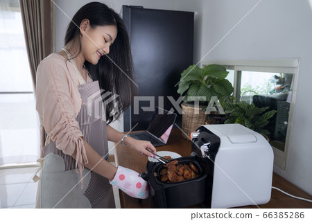 Asian girl use Air fryer machine for cook a Asian girl use Air fryer machine for cook a 66385286