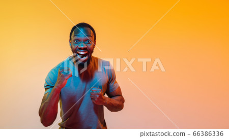 African-american man's portrait isolated on gradient orange studio background in neon light African-american man's portrait isolated on gradient orange studio background in neon light 66386336