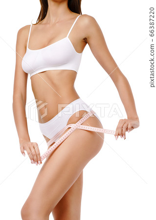 Slim tanned woman's body over gray background - waist measurement 66387220
