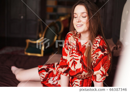 Happy young woman. Relaxed woman lying on a brown bed 66387346