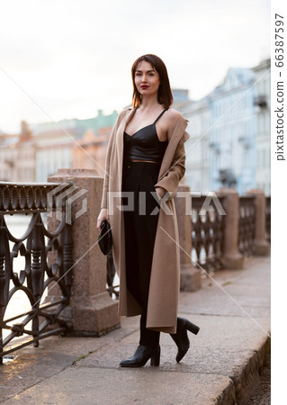 Woman in black pantsuit walks on promenade Woman in black pantsuit walks on promenade 66387597