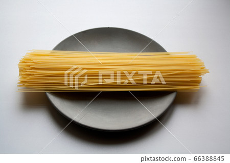 Capellini pasta heap on grey concrete plate isolated on white background Capellini pasta heap on grey concrete plate isolated on white background 66388845