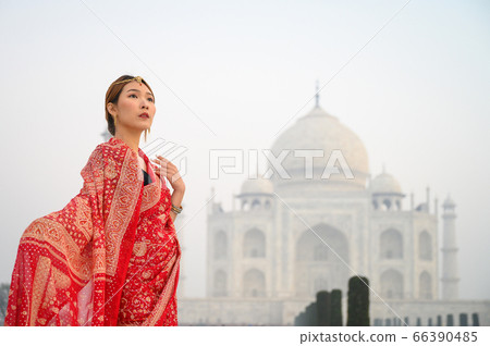 Asian woman wearing red saree indian traditional dress against Taj Mahal Asian woman wearing red saree indian traditional dress against Taj Mahal 66390485