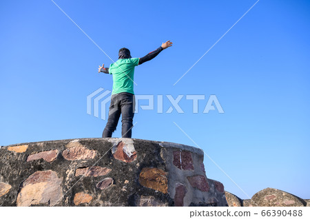 Success and Hiking concept, Man raising hands after climbed stone 66390488