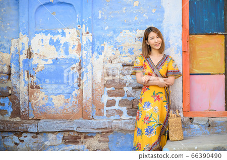 Portrait of young woman in front colorful building wall in Jodphur blue city in India 66390490