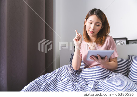 Young asian woman using tablet on bed browsing item to buy and pay with credit card Young asian woman using tablet on bed browsing item to buy and pay with credit card 66390556