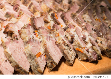 baked pork stuffed with carrots, sliced into thin slices on a wooden board. juicy slices of cooked meat close-up. 66394425