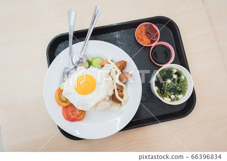 Meal at chain convenience store: fried egg and rice, a sausage, seaweed soup & fresh veggies. A closeup, a top-down view of plates on a tray.	 66396834