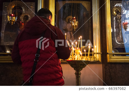 Saint Petersburg, Russia: a believer lights a candle in front of icons in Kazan Cathedral. The cathedral is one of the main centers of the religious life of the city. Saint Petersburg, Russia: a believer lights a candle in front of icons in Kazan Cathedral. The cathedral is one of the main centers of the religious life of the city. 66397082