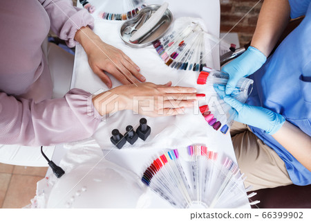 Close-up of manicurist showing schemes of polish in nail salon Close-up of manicurist showing schemes of polish in nail salon 66399902