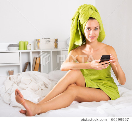 Woman in towels using her smartphone 66399967