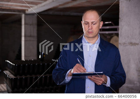 Winemaker with clipboard in wine cellar Winemaker with clipboard in wine cellar 66400056