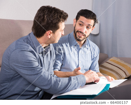 Two happy men with documents on sofa Two happy men with documents on sofa 66400137