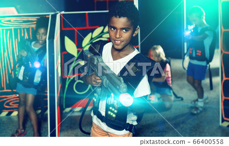 Portrait of happy cheerful preteen boy with laser pistol posing in laser tag labyrinth 66400558