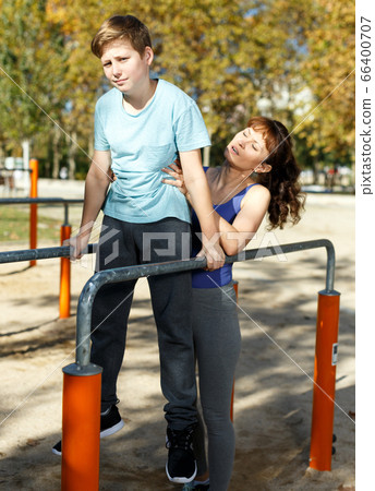 Family exercising on parallel bars outdoors 66400707