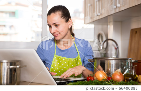 Housewife cooking and using laptop 66400883