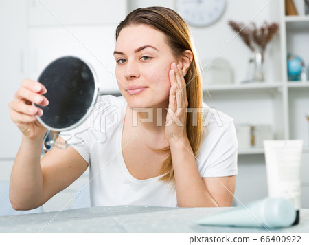 Young woman is satisfied of quality her skin in with mirror Young woman is satisfied of quality her skin in with mirror 66400922