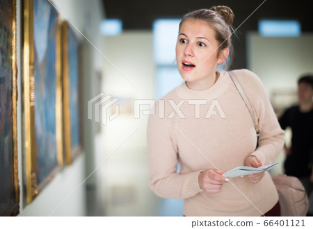 Pretty woman holding guide book in museum 66401121