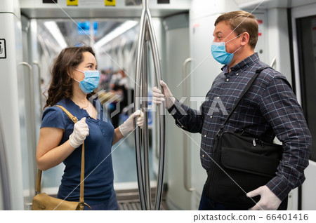 Metro passengers wearing personal protective equipment talking 66401416