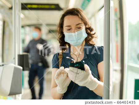 Woman in protective medical mask and gloves rides in tram 66401435