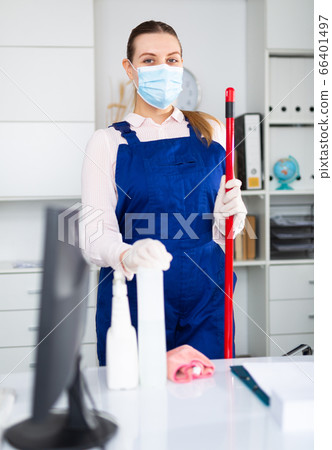 Woman professional cleaner in protective medical mask cleaning desk in office Woman professional cleaner in protective medical mask cleaning desk in office 66401497