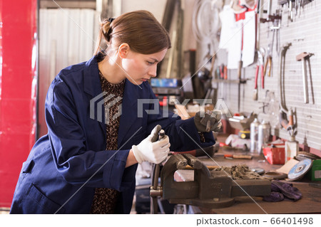 Young woman handles part on bench vise Young woman handles part on bench vise 66401498