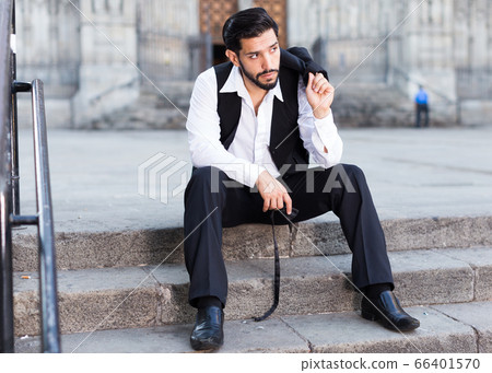 Man wistfully sitting on stone stairs Man wistfully sitting on stone stairs 66401570