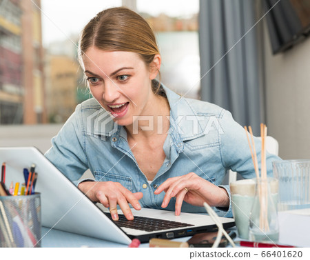 Excited woman with laptop in living room 66401620