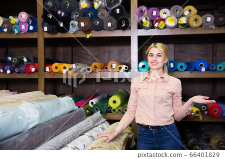 Saleswoman offering cloth in textile shop Saleswoman offering cloth in textile shop 66401829