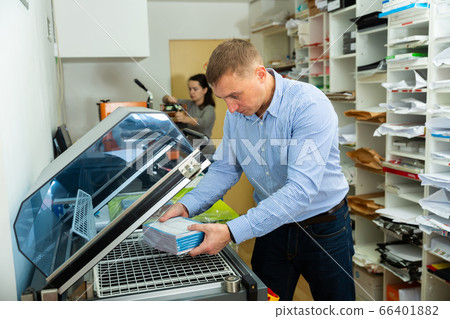 Worker packs notebooks in a vacuum packing 66401882
