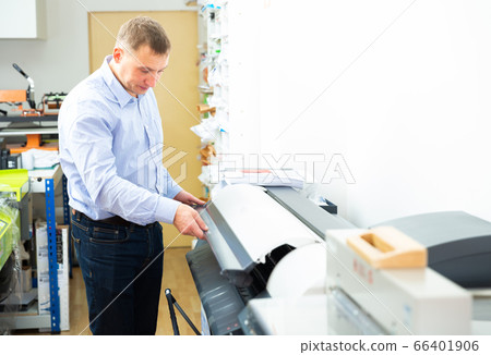 Man uses plotter in small printing shop 66401906
