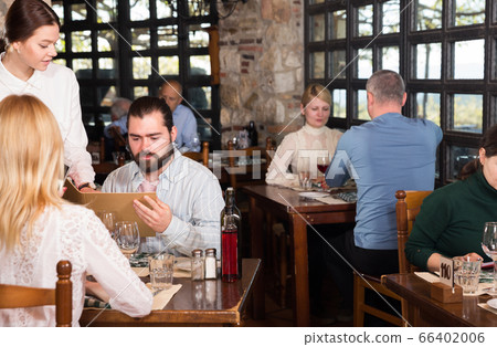 Waitress showing menu card to couple 66402006
