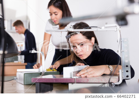 Female student using scroll saw for architectural modeling Female student using scroll saw for architectural modeling 66402271