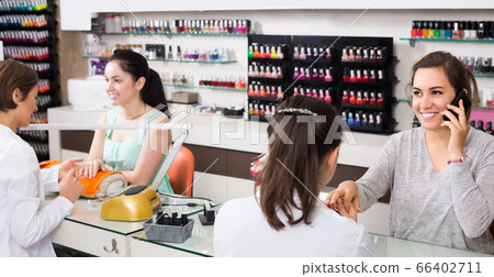 woman using smartphone during manicure at nail salon 66402711