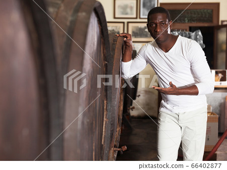 male winemaker or seller standing near wooden barrels in wine shop male winemaker or seller standing near wooden barrels in wine shop 66402877