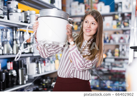 Glad woman choosing slow cooker in shop Glad woman choosing slow cooker in shop 66402902