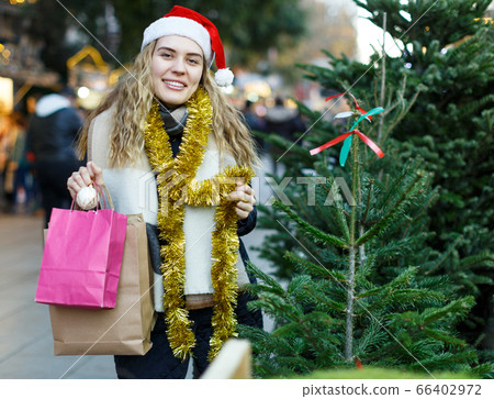 Girl in knitted hat choosing Christmas tree Girl in knitted hat choosing Christmas tree 66402972