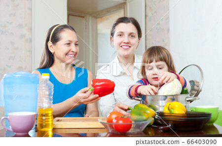 Mature woman and adult daughter with baby in kitchen 66403090