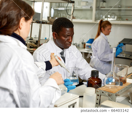 African american male lab technician writing report after chemical experiments 66403142