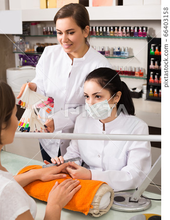 Manicurists choosing color of nail polish with client in nail salon Manicurists choosing color of nail polish with client in nail salon 66403158