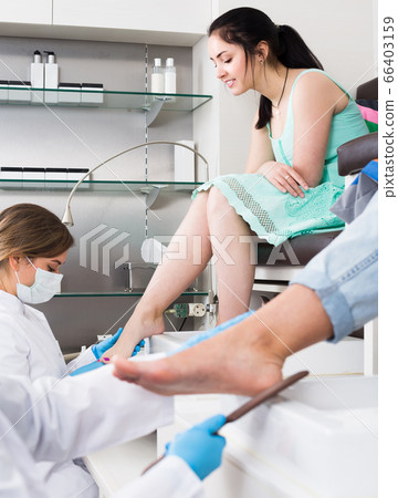Pair of women clients getting pedicure in modern nail salon Pair of women clients getting pedicure in modern nail salon 66403159
