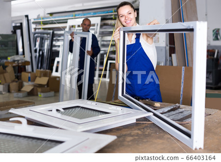female worker measuring metal-plastic window frame in workshop female worker measuring metal-plastic window frame in workshop 66403164