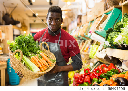 Greengrocery owner offering carrots for sale Greengrocery owner offering carrots for sale 66403306